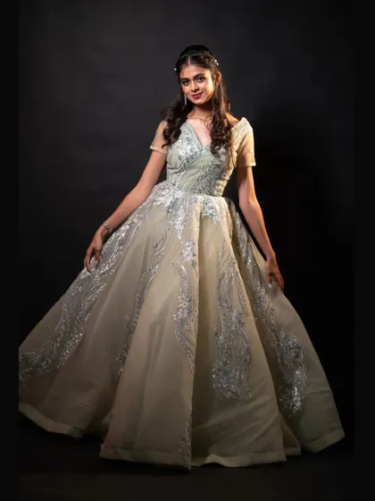A full-length shot of the light pista green ball gown against a black backdrop, making the silver embroidery pop.