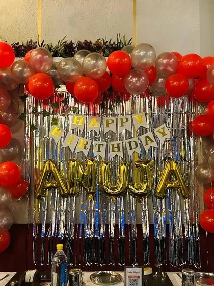 A simple restaurant table decoration with a red and silver balloon arch and personalized name balloons.