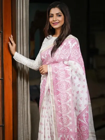A beautiful white and pink printed saree, perfect for a soft, feminine look. It’s paired here with a long-sleeved white blouse for an elegant ensemble.