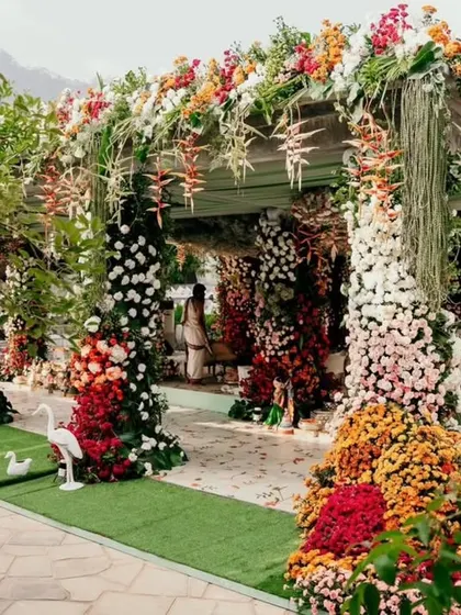 Another angle of the lush floral mandap, showing how it integrates with the natural surroundings. The design uses a variety of flowers and greenery to create a structure that feels both grand and organic.