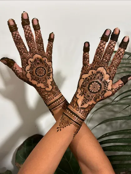 This design combines a central mandala on the back of the hand with intricate patterns that extend up the arm, creating a balanced and beautiful look for a bride or bridesmaid.