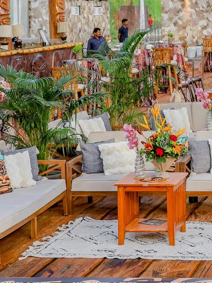A lounge area with comfortable sofas and themed cushions, set against the backdrop of the stone-walled Tiki bar.