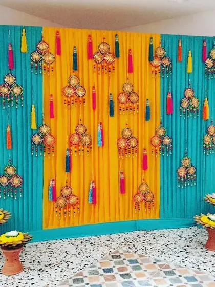 A simple and elegant backdrop for a small Mehendi function. The turquoise and yellow drapes are adorned with beautiful handcrafted tassels.