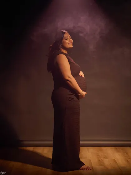 A solo portrait capturing the pure joy and anticipation of motherhood. The soft, hazy spotlight adds a dreamy, cinematic quality, focusing on her happy, sun-kissed expression.