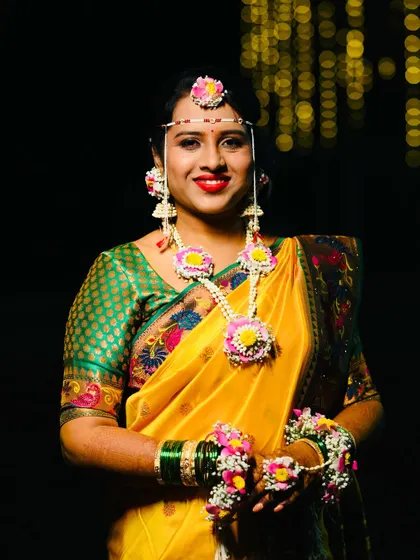 A beautiful smile from the bride-to-be. Here you can see the details of her floral necklace and jhumkas, designed to match her yellow and green saree perfectly.