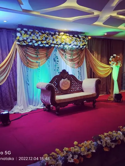 This is a classic stage setup for a convention hall wedding reception. I used a combination of gold and white drapes with floral arrangements on the top and sides, complemented by an ornate traditional sofa.