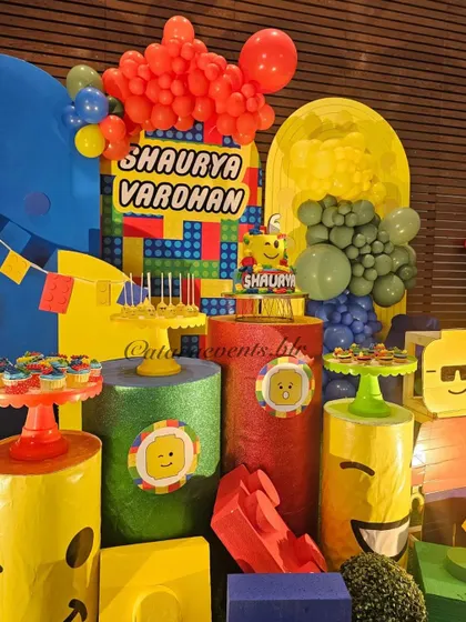 The dessert area is a colorful explosion of LEGO-themed treats and props, with smiling character faces adding to the fun.