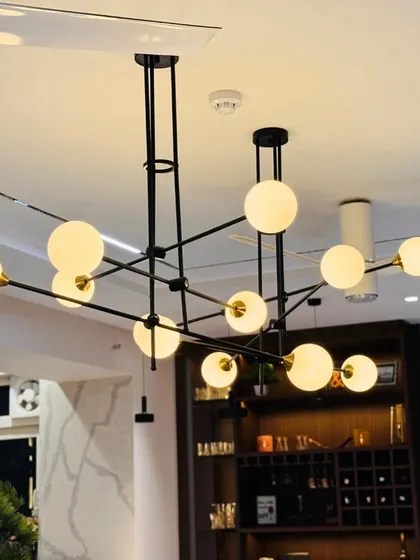 A close-up of a modern, multi-globe chandelier that acts as a sculptural centerpiece in a dining area, demonstrating my focus on statement lighting.