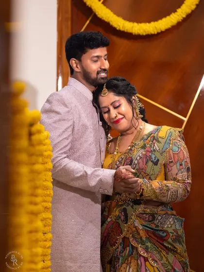 A warm, loving portrait of a couple during their housewarming ceremony, surrounded by traditional marigold flower decorations.