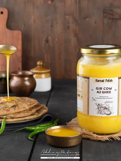An action shot of ghee being poured onto a hot paratha immediately makes the viewer feel hungry. This type of dynamic image is very effective at demonstrating the product in use and highlighting its rich quality.