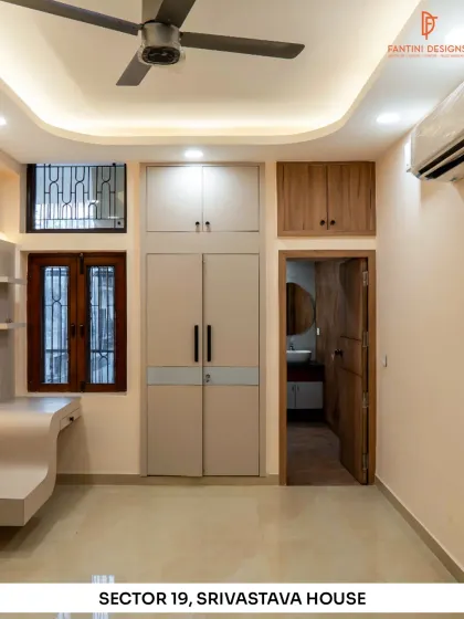 This room in the Srivastava House project shows the built-in wardrobe and study nook. The design maximizes space with a mix of closed and open storage, all finished in a calm, neutral palette.