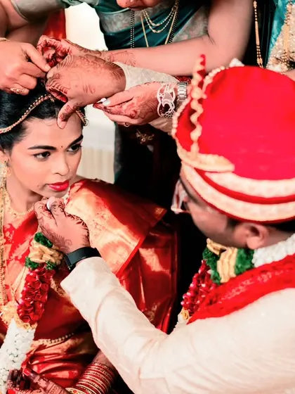 The groom applying sindoor to the bride's forehead, a deeply symbolic moment in a Hindu wedding, captured up close.