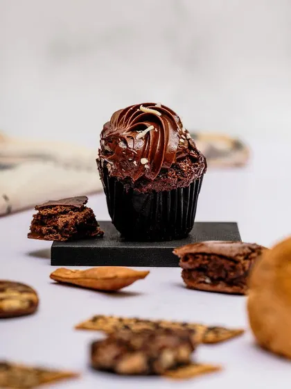 A styled shot of a chocolate cupcake, deconstructed with its ingredients around it. This tells a story about the quality of the ingredients and adds visual interest.
