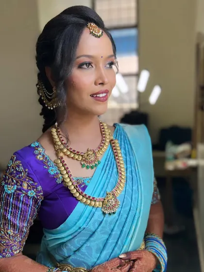 A beautiful Varapooja look for Anusha. Her bright blue saree is complemented by a soft, glowing makeup look and a traditional braided hairstyle.