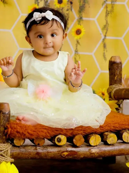 A sweet baby girl sitting on a rustic wooden bed in our honeycomb and sunflower set. The warm lantern light adds a magical touch to this enchanting portrait.