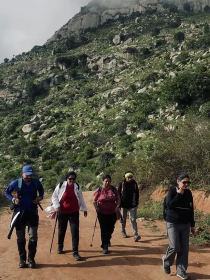 A group of colleagues trekking along a dirt path on a hillside. Our customized treks are perfect for small teams looking for a personalized adventure.