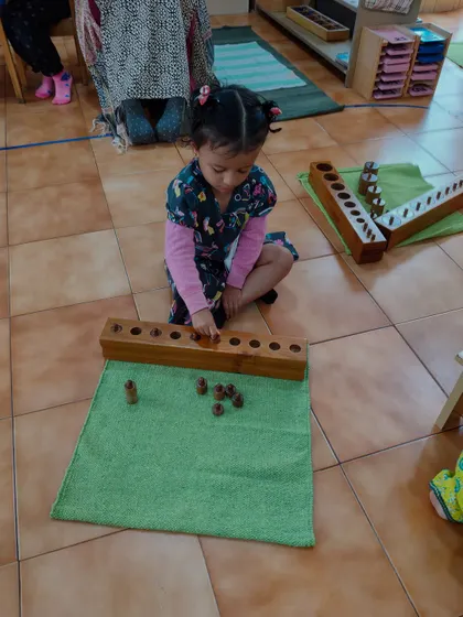 This child is deeply concentrated on the knobless cylinders. This sensorial material helps refine the ability to discriminate by size and prepares the child for understanding concepts of seriation and order.