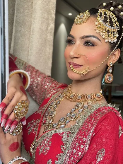A side profile showcasing the elegant hair bun and the heavy passajewellery, which complements the traditional red bridal lehenga.