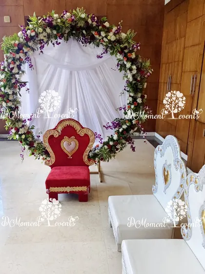 An elegant floral ring backdrop with a regal red chair, creating a perfect setting for a traditional puja ceremony like Annaprashan.