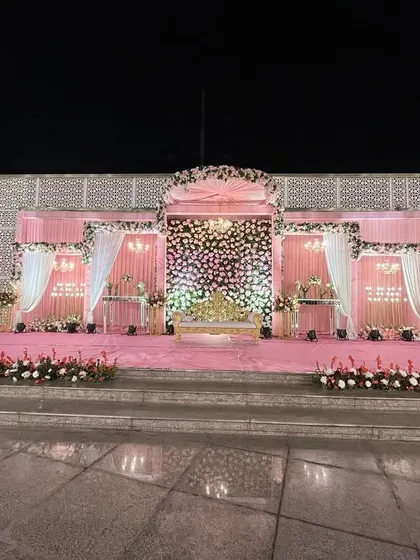 A wide view of a lovely pink and white outdoor wedding stage. The symmetrical design with a central floral arch creates a timeless and elegant look for the ceremony.