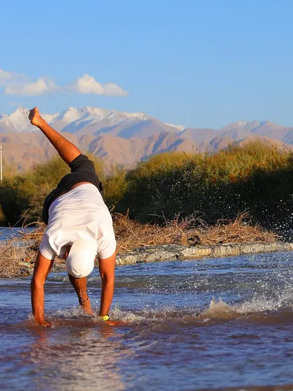 Fitness should also be fun. Here, one of our team members celebrates with a playful cartwheel in the cool river water after a tough day of training, with the beautiful mountains of Ladakh in the background.
