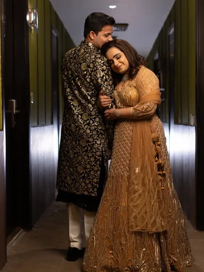A sweet, intimate moment between the couple. His classic black sherwani with gold embroidery is a perfect match for her glittering lehenga.
