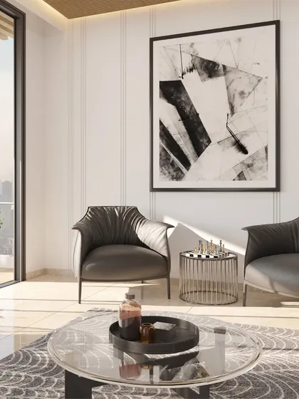 A clean, bright seating area featuring modern leather armchairs and a glass coffee table. The design uses white fluted wall panels and a large abstract art piece to create a sophisticated and light-filled corner, perfect for conversation.