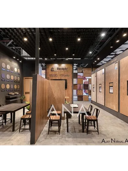 A long view of the Realply '23 interior, highlighting the organized layout of discussion tables and extensive product walls. The dark ceiling and track lighting create a focused, gallery-like atmosphere.