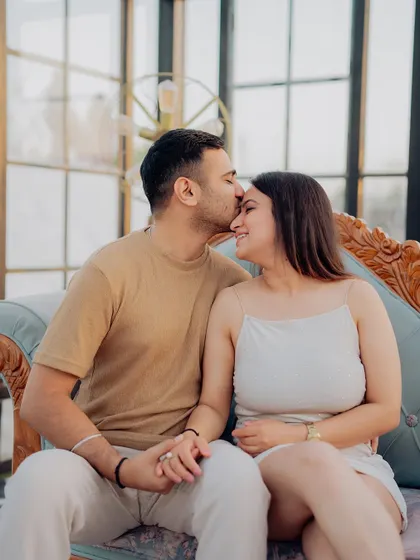 A close-up of a tender forehead kiss, showcasing the couple's affection in the soft, natural light of the conservatory.