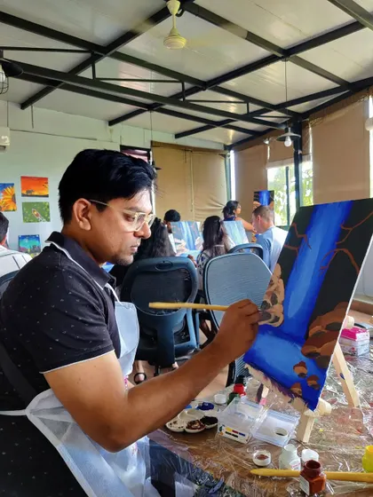 A painter completely absorbed in his work, adding the final touches to a waterfall scene. Our workshops are a great way to block out the noise and just focus on creating.