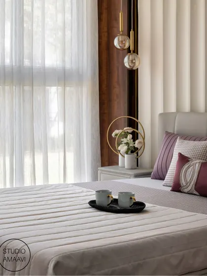A quiet morning moment in a beautifully designed bedroom. The focus is on the soft light filtering through sheer curtains and the elegant details of the bedside, including pendant lights and a decorative vase, creating a peaceful and inviting scene.