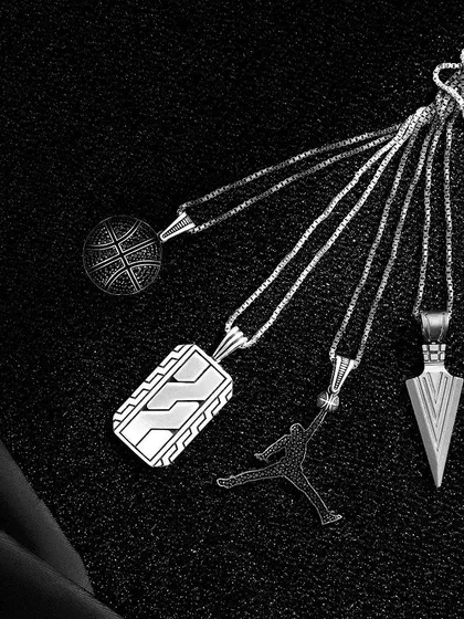 A creative flatlay of Orionz Jewels pendants. The pieces are clustered together to look like a bouquet of unique designs, shot with dramatic lighting to emphasize their texture and form.