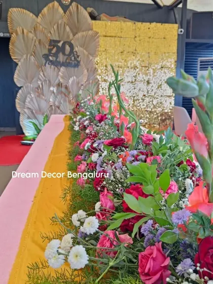A beautiful floral table runner for a 50th-anniversary lunch. Using fresh, colorful flowers is a great way to make a dining setup feel special and luxurious.