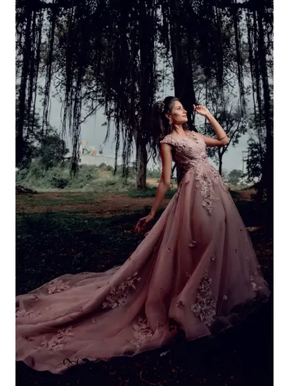 This light pink wedding gown, with its long, detailed train and 3D floral embellishments, is the epitome of fairytale romance for a pre-wedding shoot.