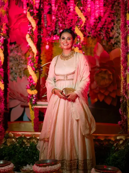 A smiling portrait of Kavya Gowda, with the vibrant pink and yellow lighting of the event creating a festive mood.
