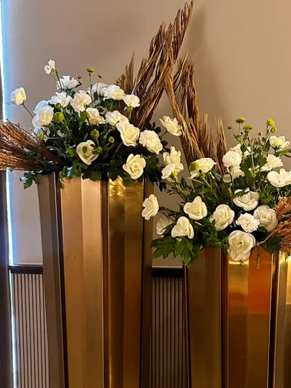 Elegant gold vases holding arrangements of white roses and dried grasses, adding a touch of sophisticated glamour to the space.