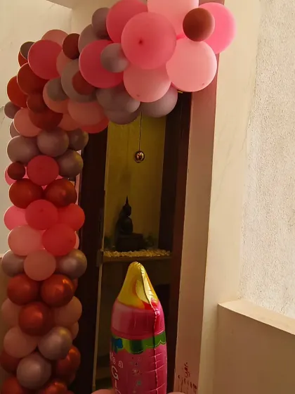 A beautiful balloon arch in shades of pink creates a grand entrance for a baby girl's homecoming. Details like the "It's a Girl" milk bottle balloon add a playful and personalized touch.