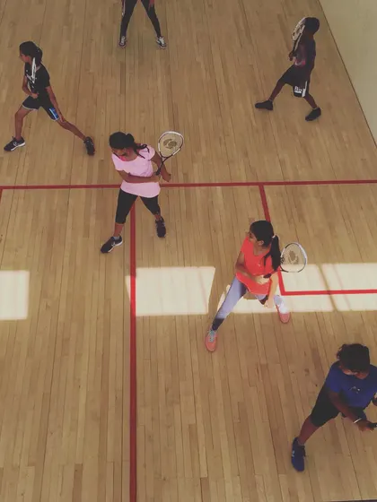 Players hold a lunge position, preparing their racquets for the next shot in a group drill. This exercise builds muscle memory for correct positioning and readiness during a rally.