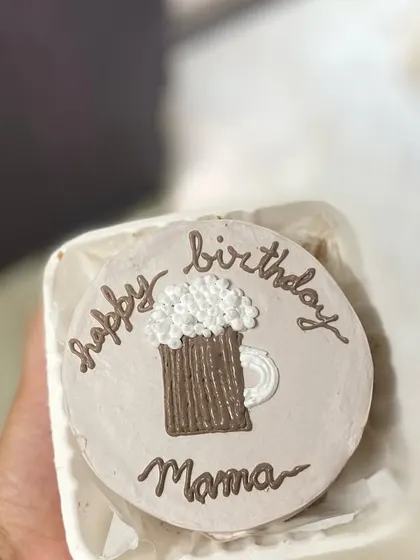 A hand-held view of the beer-themed bento cake, showing off the cute and detailed piping work.