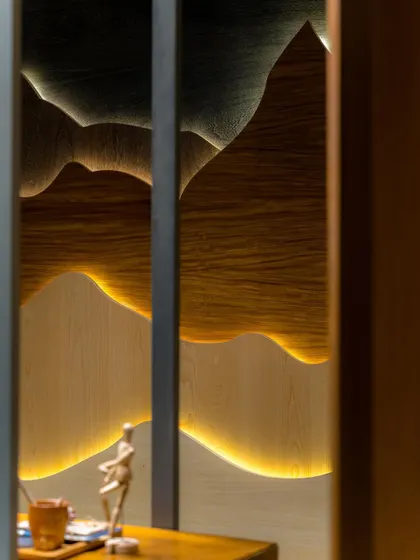 A close-up of the backlit, mountain-inspired veneer wall art, which adds a warm, ambient glow to the space.