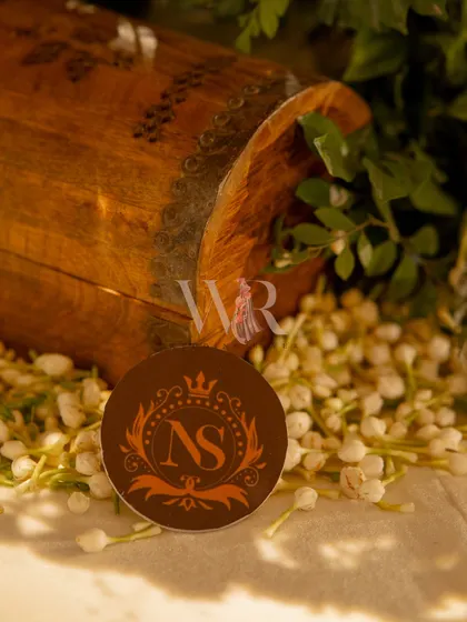 A personalized touch for the couple, Nehal and Siddharth. Their custom monogram is elegantly displayed on a small disc, surrounded by fresh mogra flowers, tying their identity into the decor.