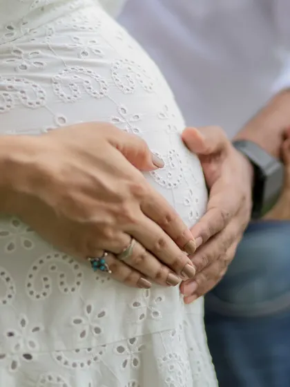 A close-up shot focusing on the hands of the parents-to-be forming a heart on the baby bump. It’s a simple, beautiful symbol of their love for their coming child.