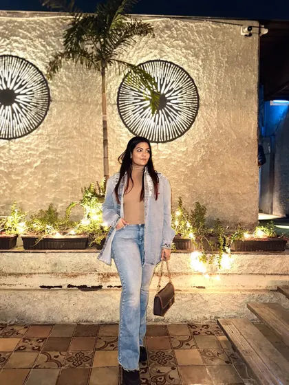 A relaxed evening look featuring a light-wash denim shirt worn open over a nude top and matching flared jeans.