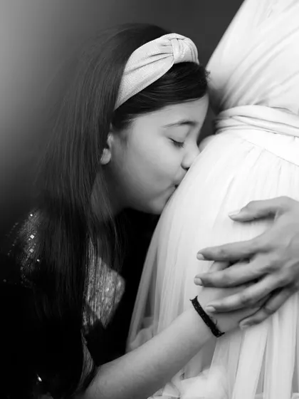 A sister's love begins even before the first hello. This touching black and white photo captures an older sister's gentle kiss, a promise of the bond to come.