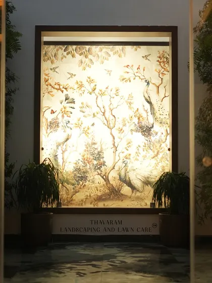 We blend art with nature to create serene focal points. This beautifully illuminated wall mural, featuring peacocks and foliage, is flanked by plants to create a captivating and peaceful entryway.