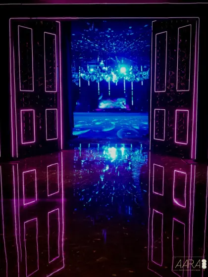 The entrance to our neon after-party, where glowing pink doors open into a universe of light and reflection. The mirrored floors and ceiling create an infinite, immersive experience for guests.
