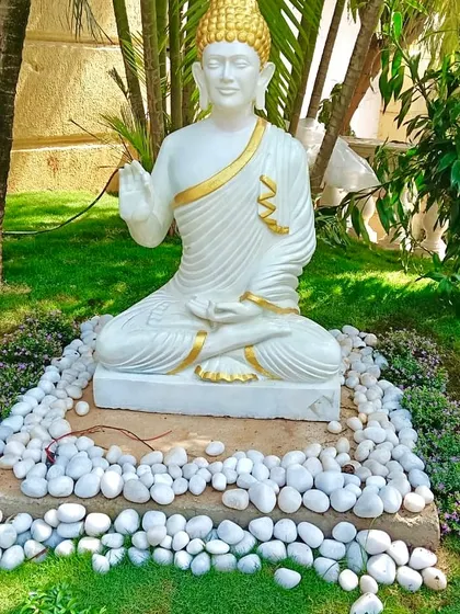 Creating a tranquil corner in a garden with a Buddha statue, surrounded by carefully selected plants and a bed of white pebbles. I focus on these details to build a specific atmosphere for my clients.