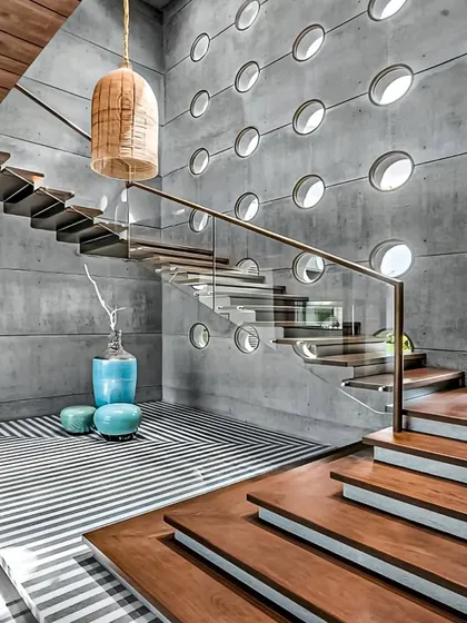 We designed this dramatic foyer with a floating staircase and a striking concrete wall featuring circular cutouts. This architectural feature not only adds visual interest but also allows light to filter through the space.