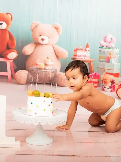 Reaching for the prize. This shot captures the baby's curiosity and excitement as he gets his first touch of the birthday cake.