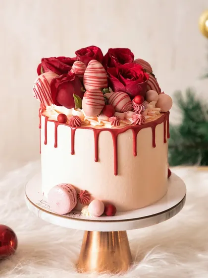 Pretty in pink and red for Christmas. This drip cake is a beautiful alternative to traditional designs, topped with roses and macarons.